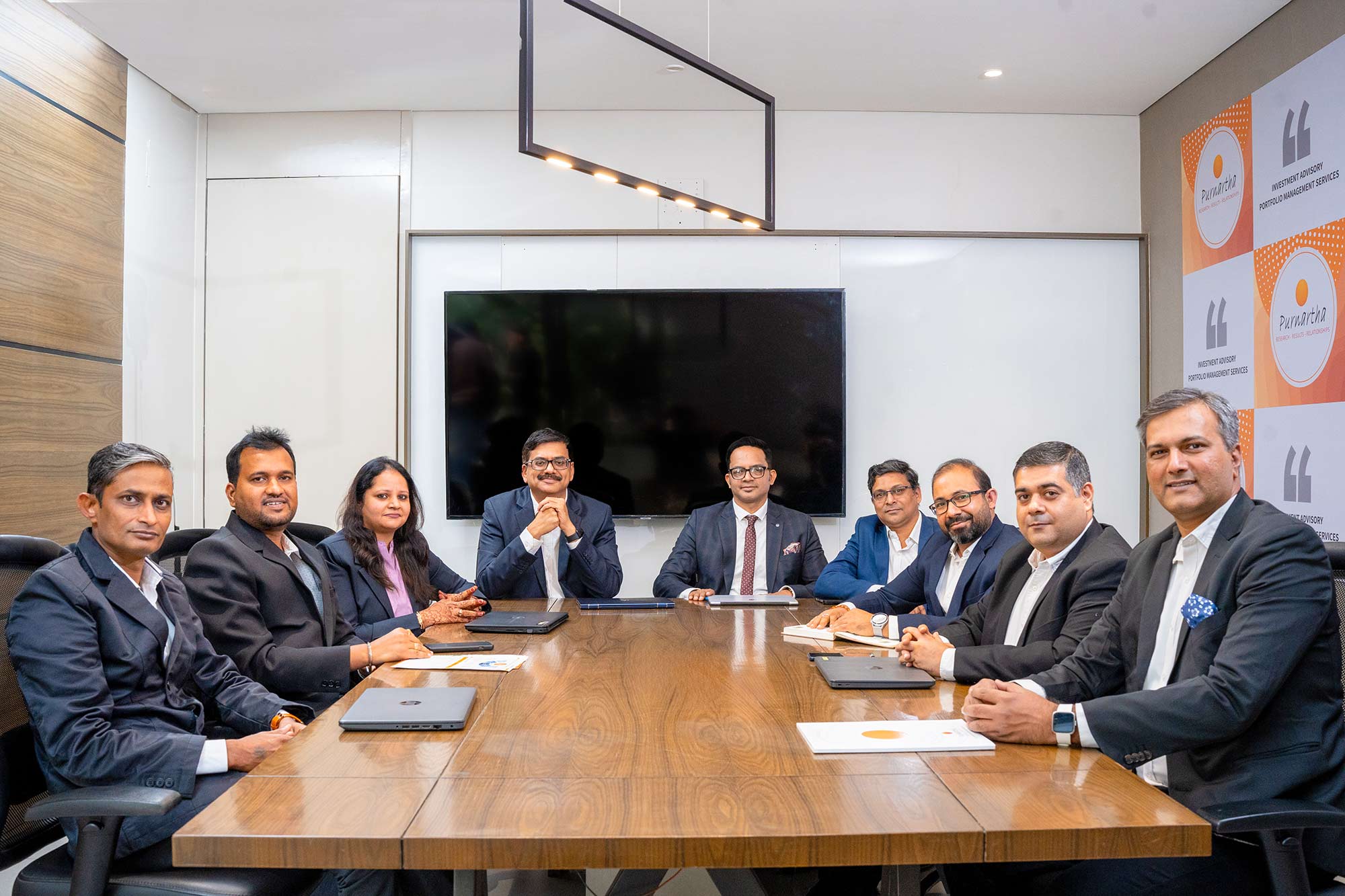 A group of individuals from Purnartha seated at a conference table, actively participating in a meeting with documents and laptops.